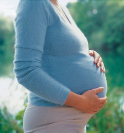 Pregnant woman holding her stomach outdoors